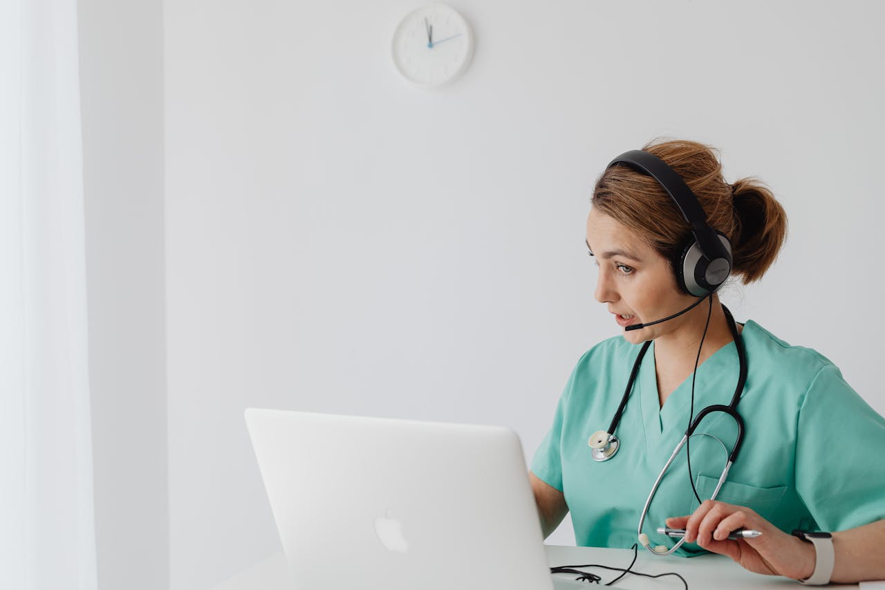 Medical professional using laptop and headphones for an online consultation in a modern office.